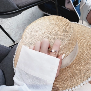 Detail of floral ring featuring purple pear-shaped gem and white flower on hand