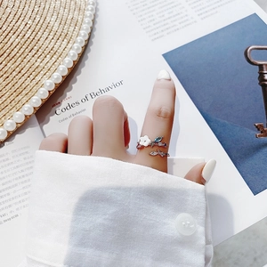 Detailed view of silver flower ring with blue gemstones and diamonds worn on finger