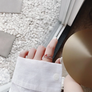 Close-up of stacked rose gold flower rings with red rubies and crystals on hand