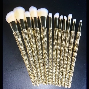 Detail of 12 luxury makeup brushes with champagne gold rhinestone handles on black background