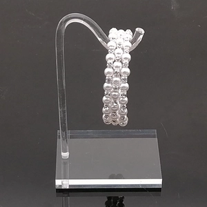 Three-layer faux pearl bracelet with silver rhinestone spacers on acrylic stand