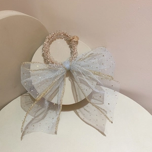 Close-up of light blue mesh bow hair tie with gold sequins and elastic coil band
