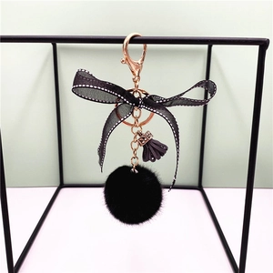 Detail of black plush keychain with polka dot bow and rose gold hardware on metal stand