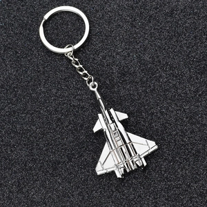 Silver fighter jet metal aircraft keychain on a professional black sparkling background