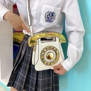 Detail of creative vintage telephone crossbody bag with white PU and gold dial panel