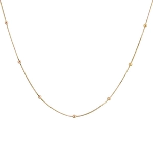 Detailed close-up of a minimalist gold snake bone chain necklace with small round beads