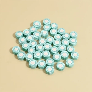 Macro shot of 10mm green polymer clay beads with pink and white spiral stripes for DIY