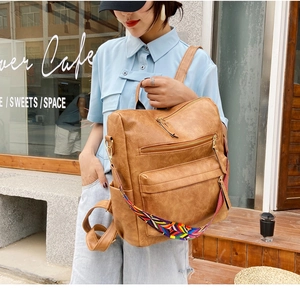 Détail d'un sac à dos vintage en cuir marron avec bandoulière ethnique tissée colorée
