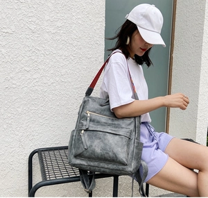 Détail du sac à dos en similicuir gris foncé mat avec bandoulière à rayures colorées