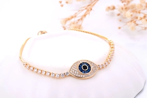 Detail van een gouden Evil Eye tennisarmband met blauwe zirkonen op een wit plateau