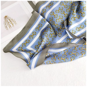 Detail of silk-like scarf with blue stripes and gold chain patterns on white background