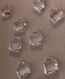Macro detail of mini crystal bag pendant with gold handle and transparent finish