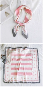 Detail view of a pink and white striped silk scarf with star patterns and grey border