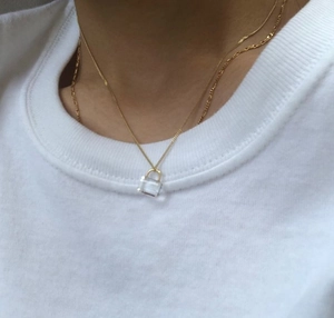 Close-up of gold chain necklace with a clear square pendant on model neck