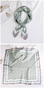 Detail of light blue silk square scarf with horsebit pattern and striped border