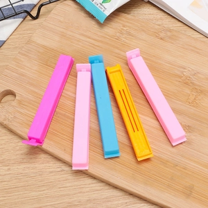 Set of 5 colorful 11cm plastic food sealing clips on a wooden board in a kitchen setting