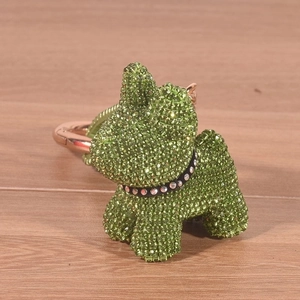 Detailed close-up of a green rhinestone puppy keychain on a wooden surface with bright lighting
