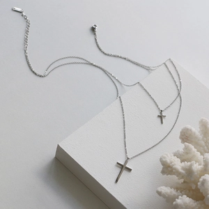 Dettaglio di collana a doppio strato argento con croci su sfondo di pietra bianca