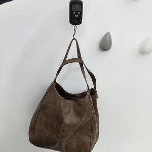 Close-up of lightweight brown leather tote bag on scale weighing only 0.52kg