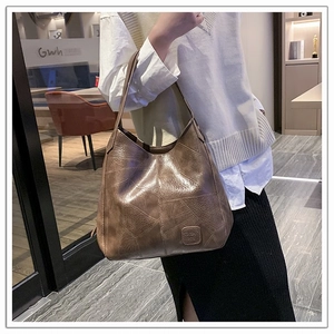 Close-up of vintage brown leather tote bag with geometric patchwork and embossed logo