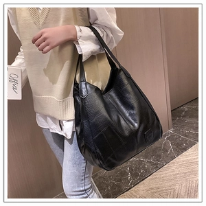 Detail of black faux leather tote bag with crocodile texture and long shoulder straps