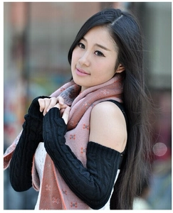 Close-up of black cable knit long fingerless gloves on a model in an outdoor setting