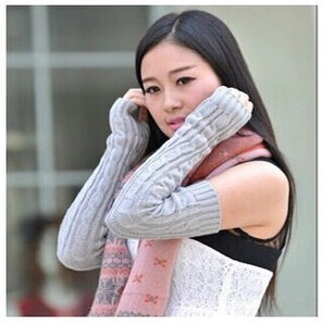 Detail of grey cable knit fingerless gloves showing thick texture and warm arm sleeve design