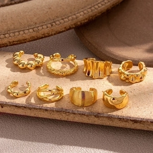 Detailliertes 8er-Set goldene Ohrmanschetten mit Texturen auf einem Steinständer