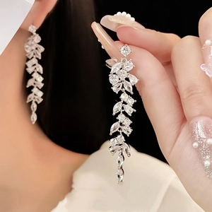 Detailed view of silver branch drop earrings with zirconia tassels on model's hand