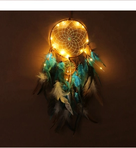 Detail of dream catcher with warm LED lights, blue and brown feathers on dark background