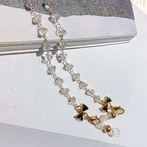 Transparent crystal glasses chain with black bow and gold finish on a minimal book background