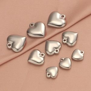 Detailed view of silver heart charms in various sizes on a pink silk background