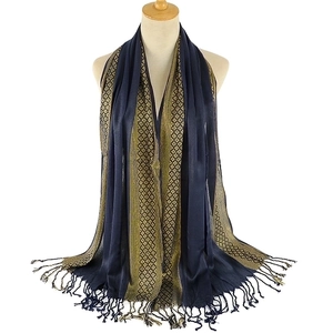 Detail of navy blue shawl with golden ethnic pattern and fringe on a mannequin
