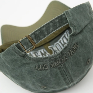 Detail of adjustable metal buckle and New York City embroidery on washed cotton baseball cap