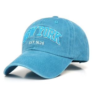 Macro detail of the white New York embroidery on washed blue cotton baseball cap fabric