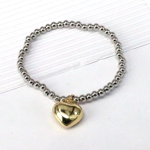 Elastic beaded bracelet with silver round beads and a gold heart-shaped pendant detail