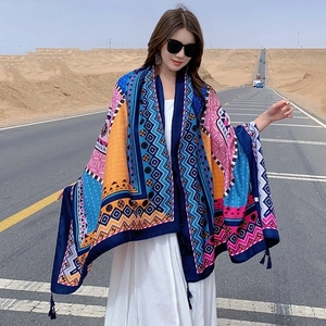 Close-up of bohemian red floral print beach shawl with fringe edges on desert road