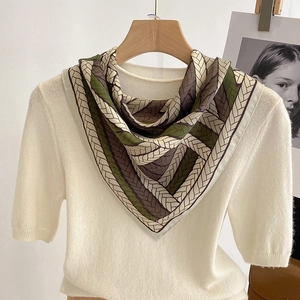 Chic square silk scarf with woven pattern tied on a cream knit top for stylish look