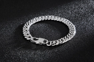 Close-up of silver titanium steel curb chain bracelet with lobster clasp on black background