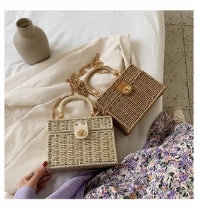 Detailaufnahme der gewebten Strohtasche mit goldener Kette und metallischem Drehverschluss