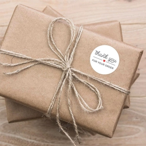 Macro shot of round white Thank You For Your Order stickers on craft gift packaging
