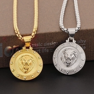 Macro shot of gold and silver lion head pendants with box chain on dark background
