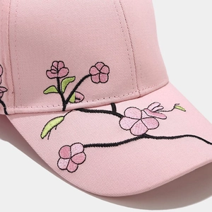 Detailed close-up of pink peach blossom embroidery on the cotton baseball cap texture