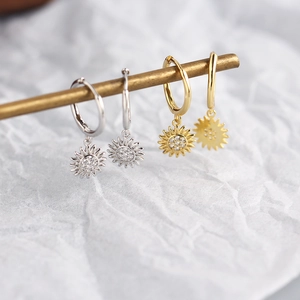 Close-up of silver and gold sunflower drop earrings with zircon crystals on a rod