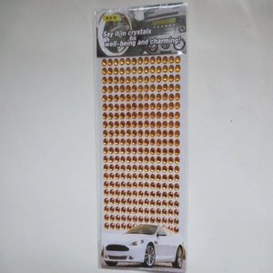Macro detail of 3mm amber acrylic rhinestone sticker sheet in transparent packaging