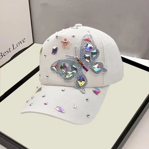 Detail of white baseball cap featuring colorful butterfly rhinestones and pink floral accents
