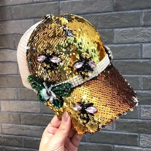 Close-up of golden sequins baseball cap featuring 3D bee and butterfly beadwork