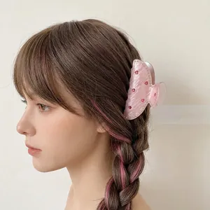 Pince à cheveux rose à motif de cœur avec strass portée sur cheveux bruns
