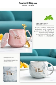 Close-up of marble texture ceramic mugs with gold rim and leaf-shaped metal spoon
