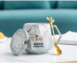 Detail view of marble pattern ceramic mug set with golden leaf spoon and cover